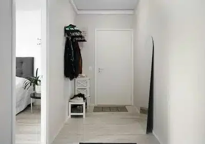 Blick in einen Wohnungseingang/Garderobe, Jacken hängen an der Wand, Schuhe sind ordentlich auf der Mini-Schuhablage abgestellt